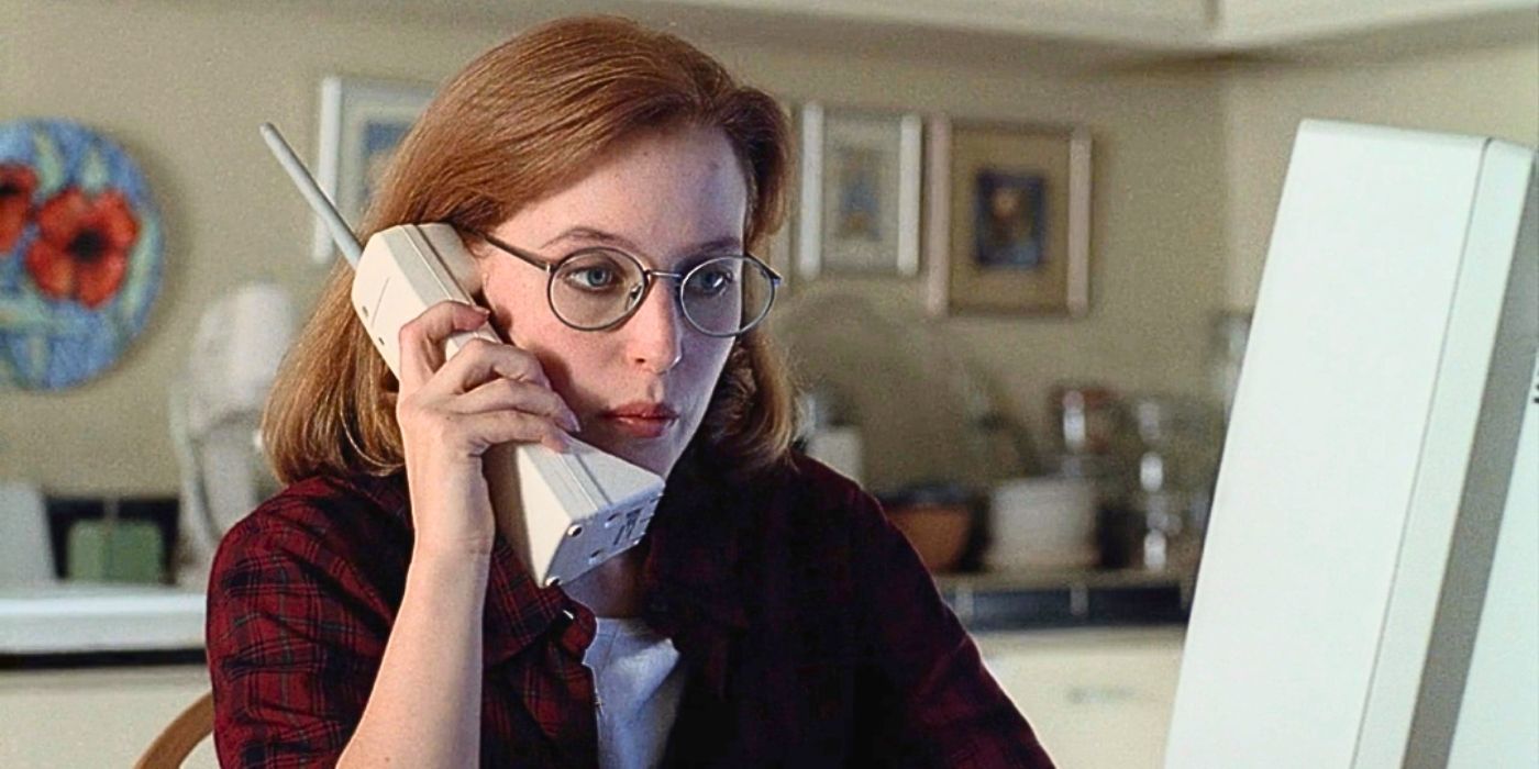 Gillian Anderson wears a red flannel shirt while holding a vintage cordless phone from The X-Files