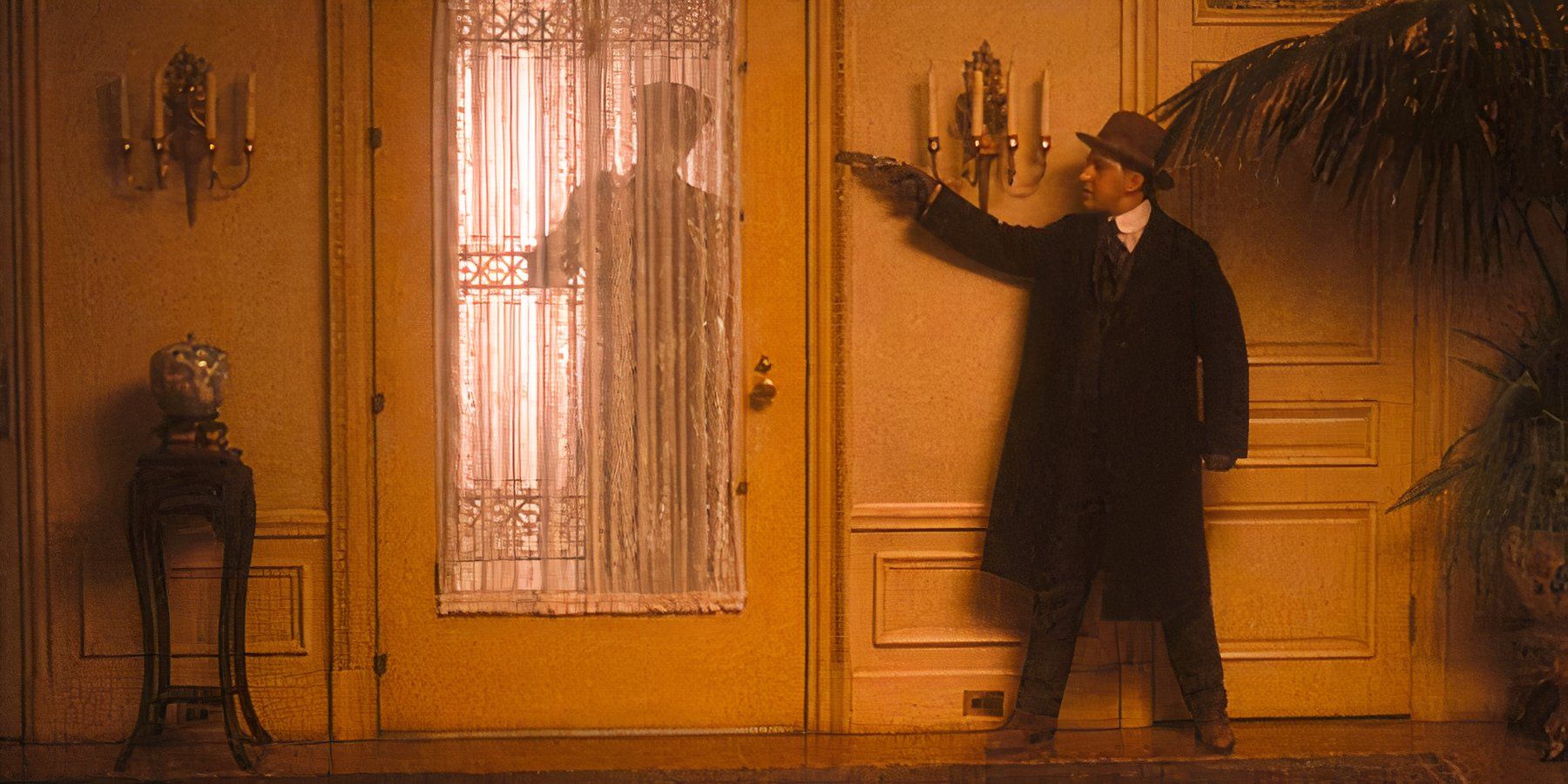 Peter Clemenza readies his revolver next to a door as the silhouette of someone approaches through the glass in The Godfather Part II.