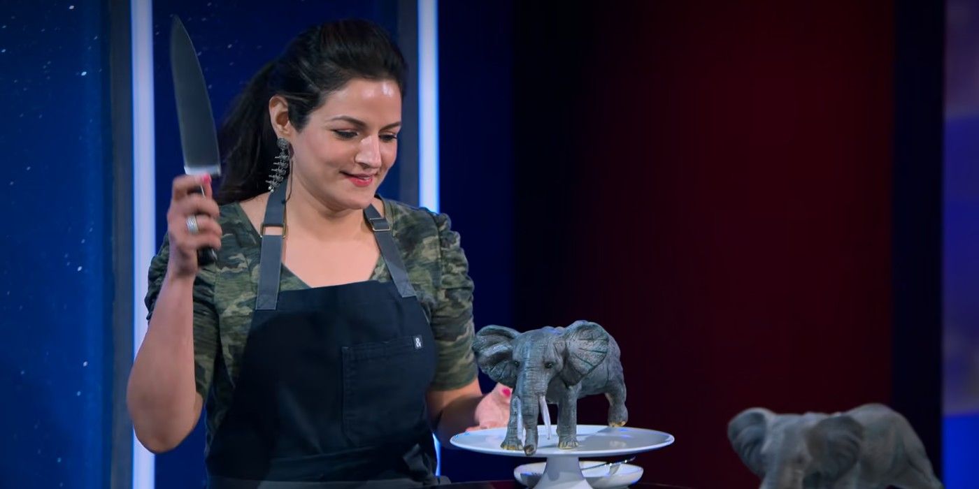 Hemu stands with a knife raised, ready to cut into her toy elephant cake on Netflix's Is It Cake