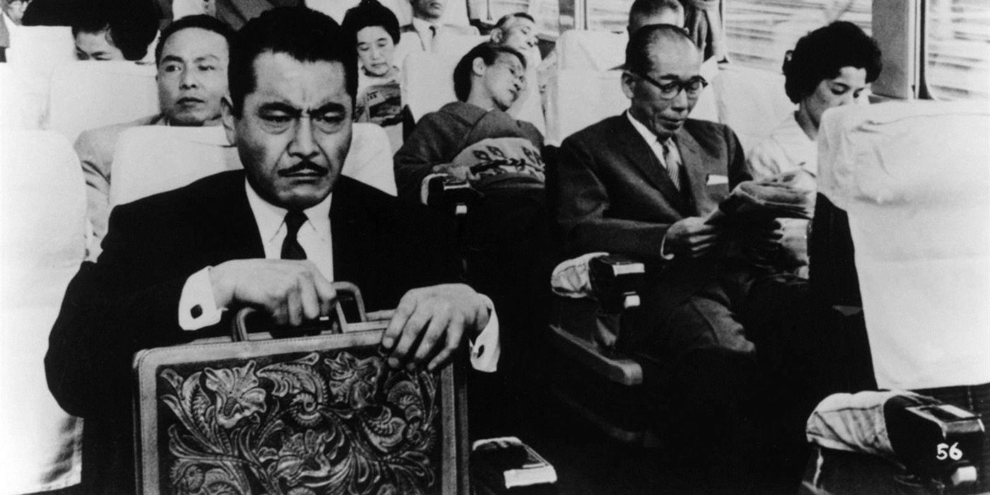 Kingo Gondo holding a briefcase while sitting in a train in High and Low