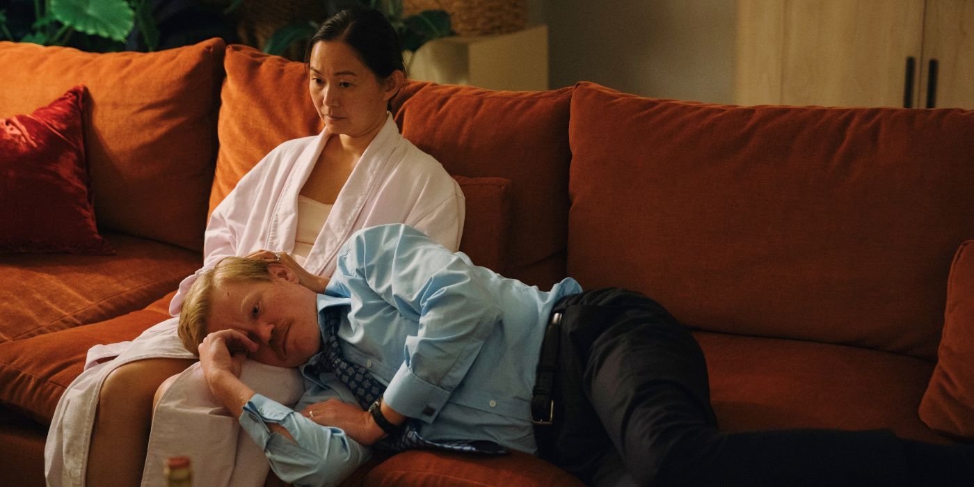 Jesse Plemons lying down on an orange sofa with his head resting on Hong Chau's lap.