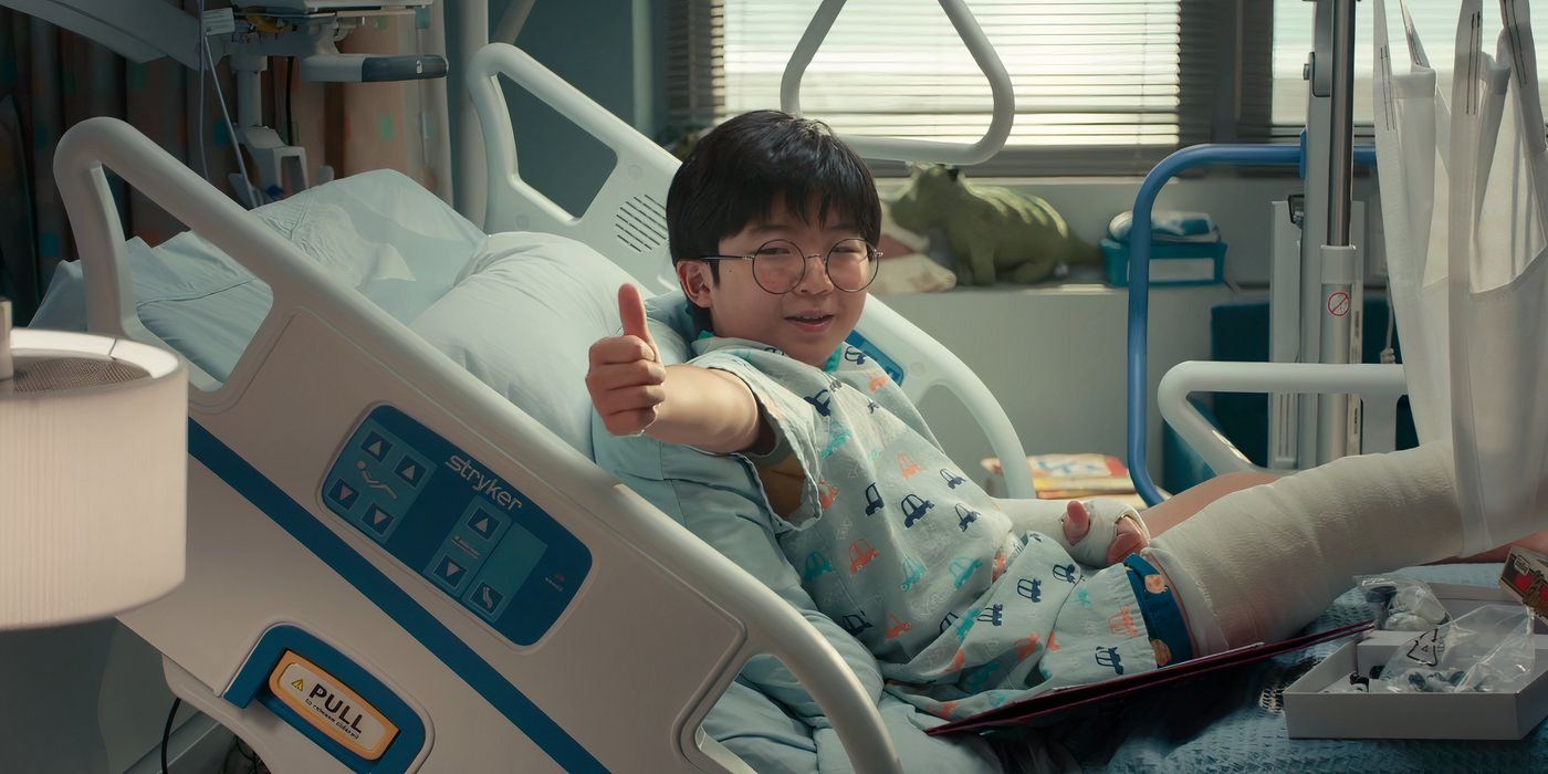 Alan Kim sitting in a hospital bed giving a thumbs up.