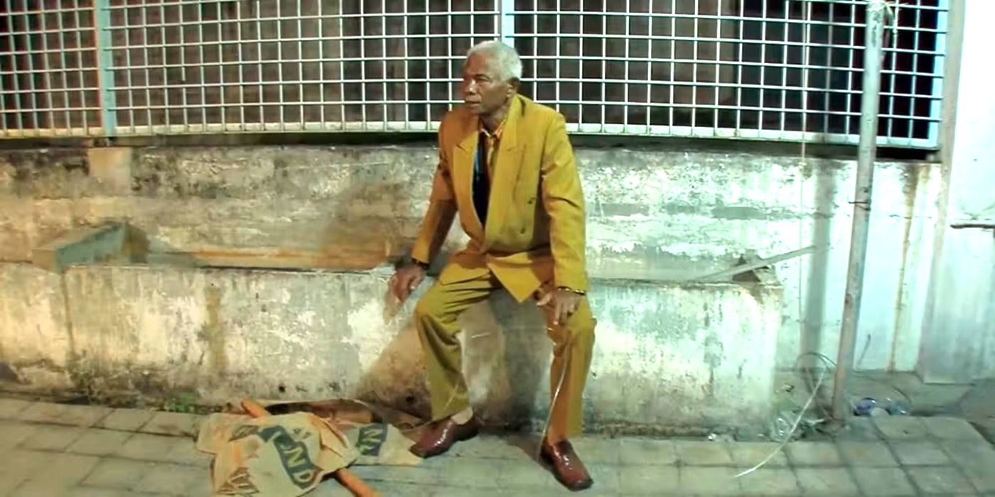 Anwar Congo sitting on a stone wall in the conclusion of The Act of Killing