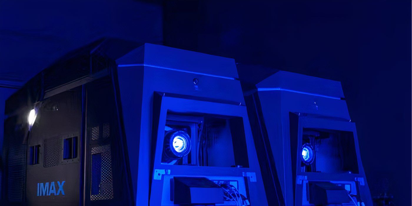 IMAX cameras illuminated in a blue light projecting onto a screen off-camera