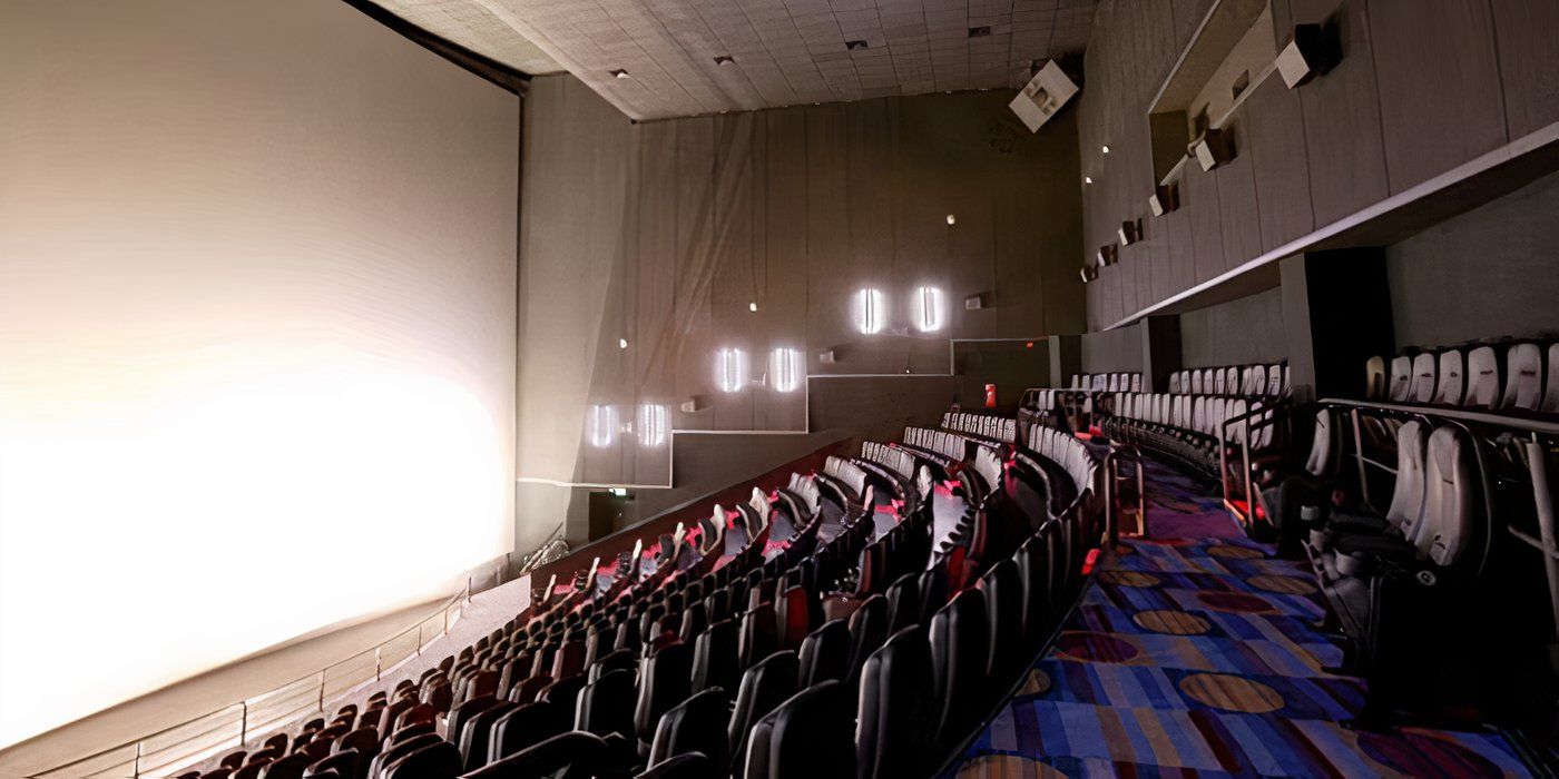 Imagem de um teatro IMAX vazio com as luzes laterais acesas e uma tela em branco