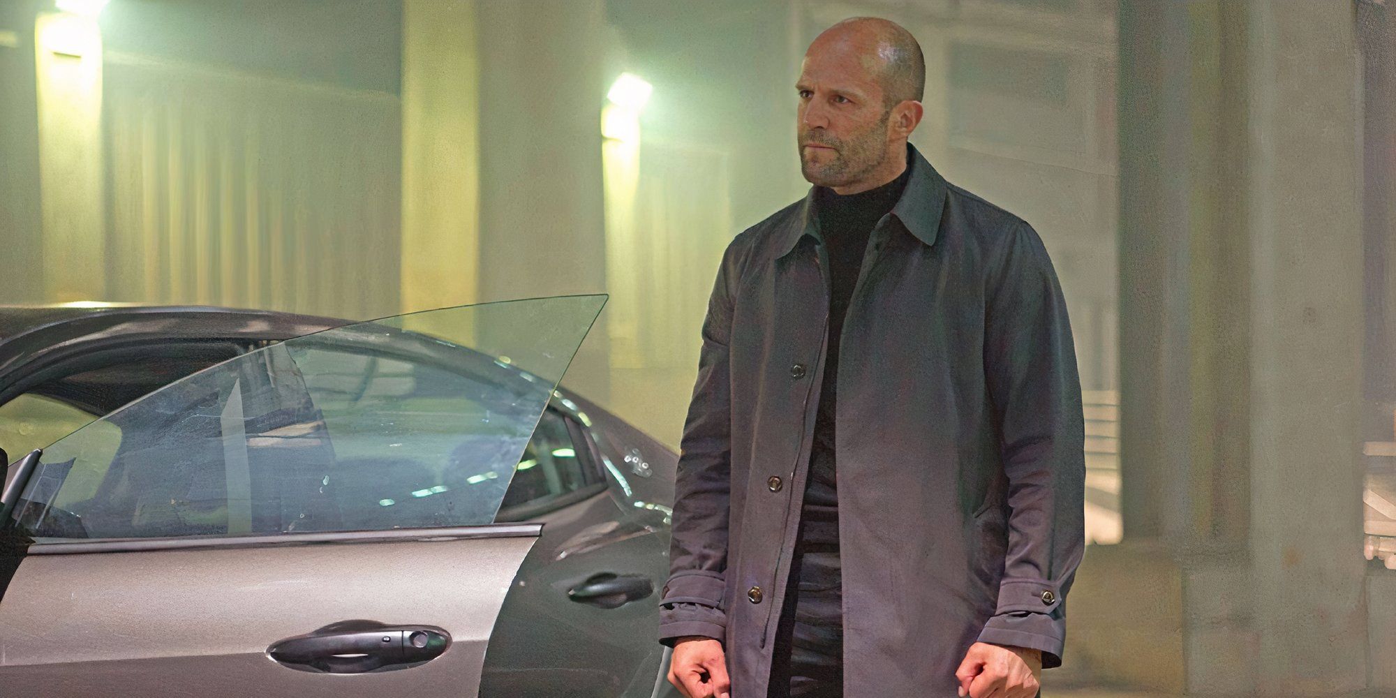 Jason Statham as Deckard Shaw in Furious 7 standing next to a car with his fists clenched.