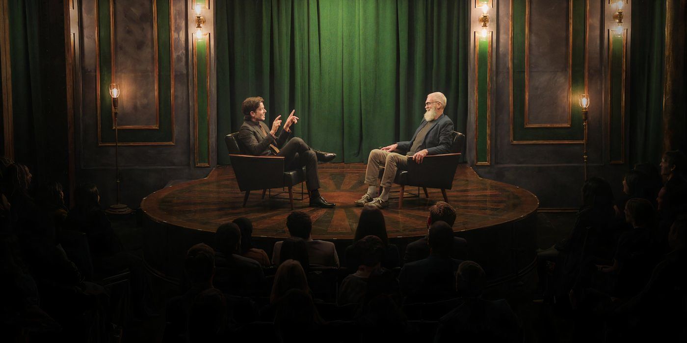 John Mulaney and David Letterman sitting in chairs and talking on a round stage.