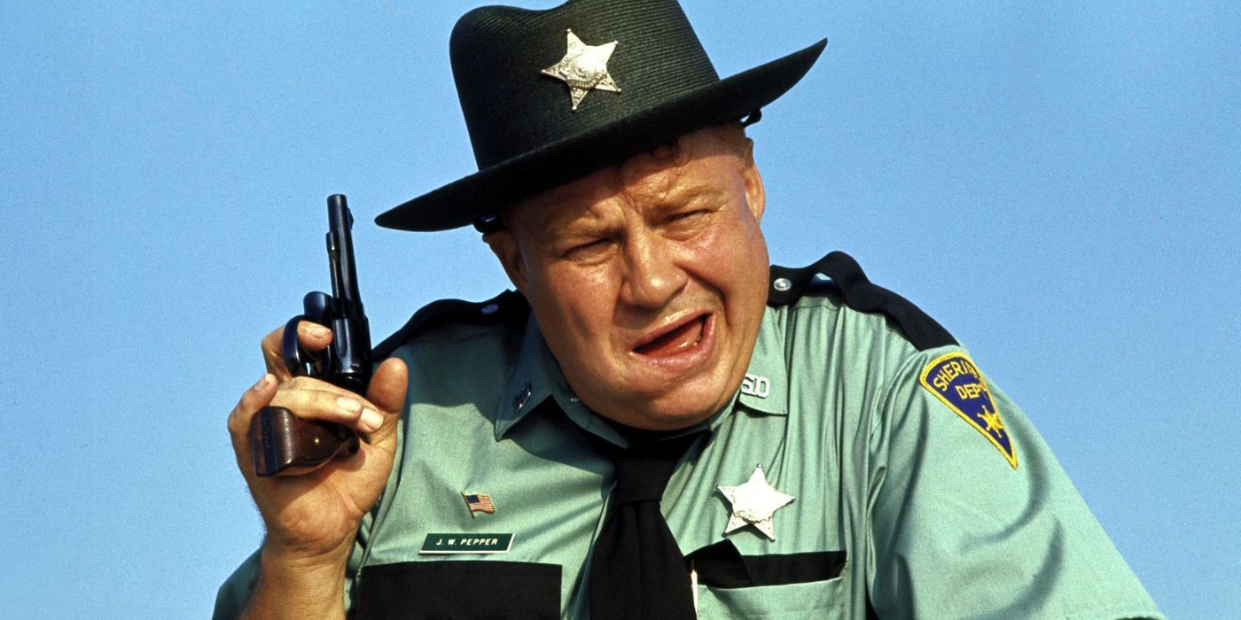 Clifton James as Sheriff JW Pepper, holding his pistol and gurning