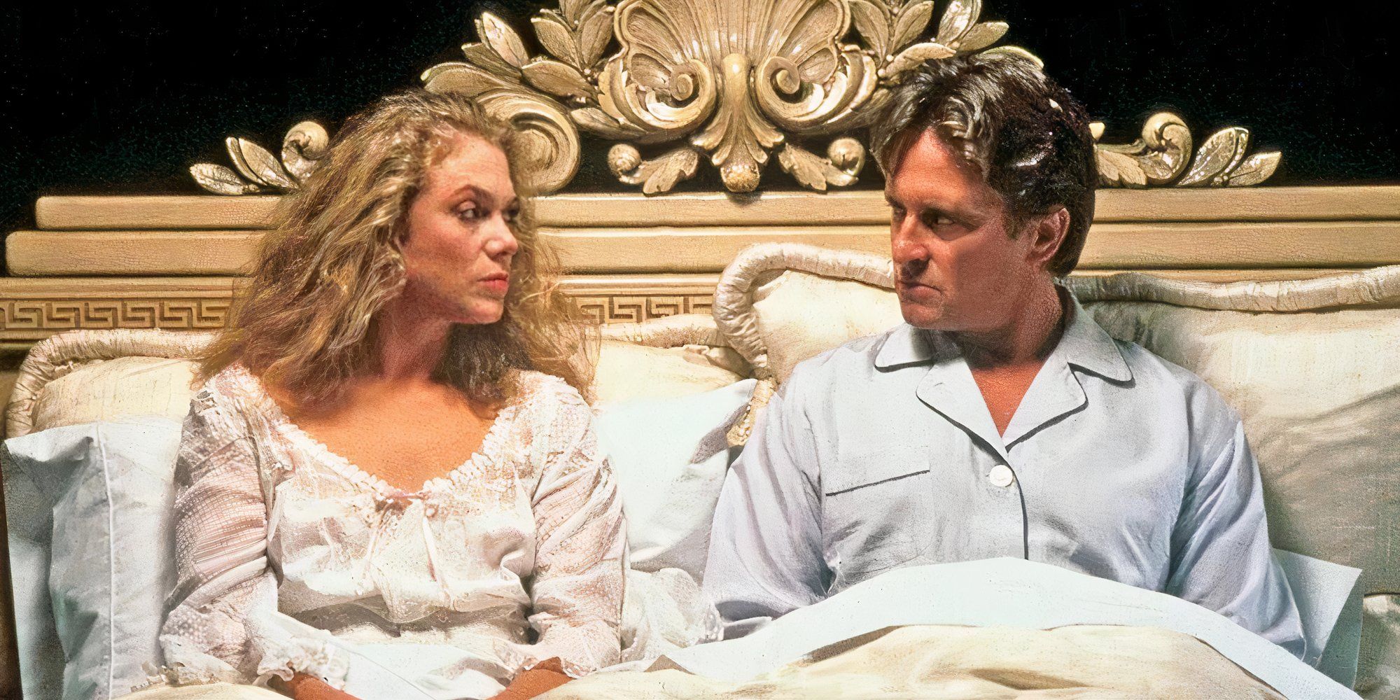 Kathleen Turner and Michael Douglas sitting up in bed and staring at each other in The War of Roses (1989)