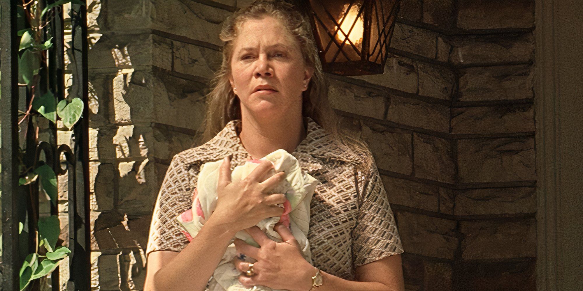 Kathleen Turner standing on the front porch clutching a piece of material to her chest in The Virgin Suicides (1999)