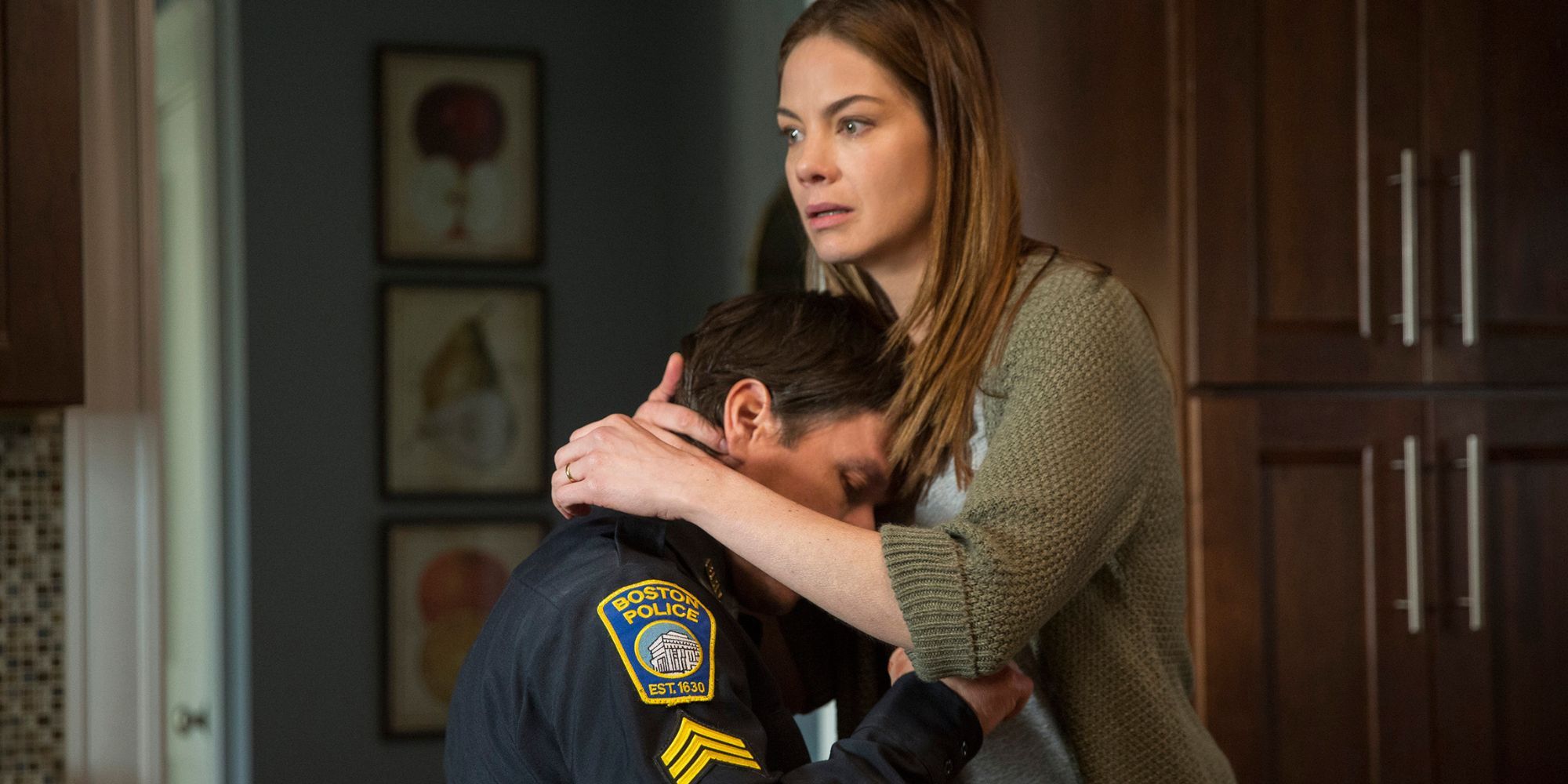 Mark Wahlberg sitting as Michelle Monaghan hugs him close to her in Patriots Day (2016)