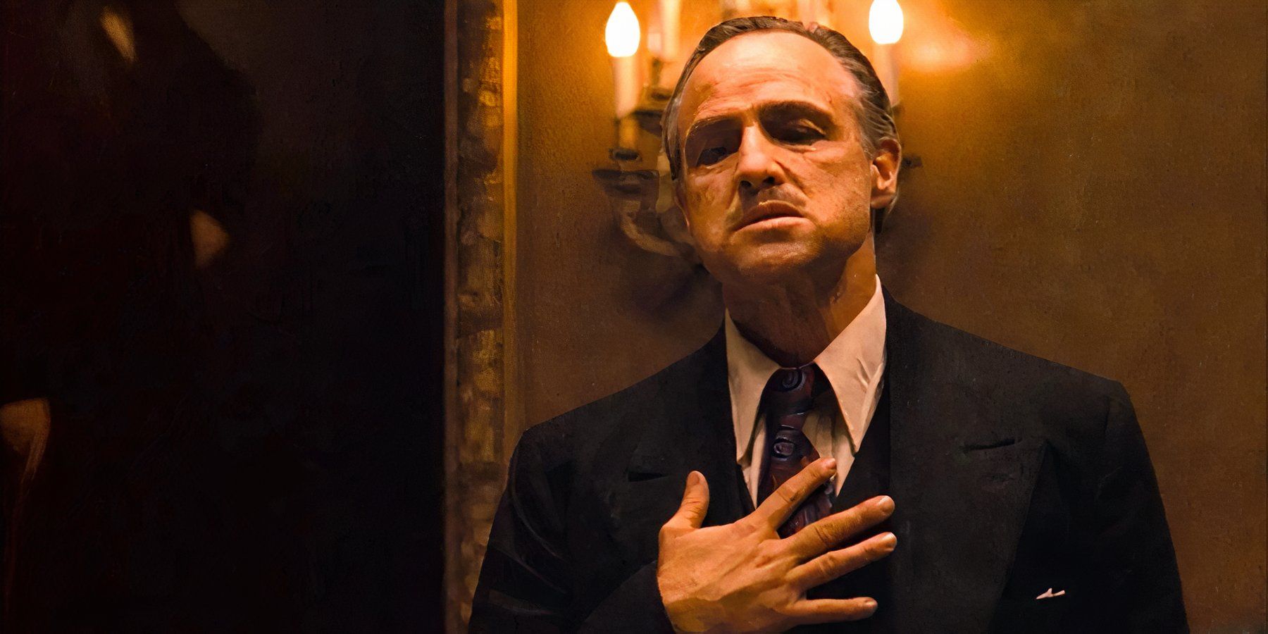 Don Vito Corleone coloca a mão no coração para um voto sombrio em O Poderoso Chefão.