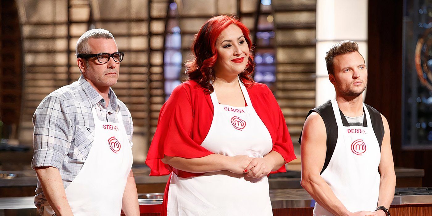 A woman with pink hair smiling flanked by two men, all three wearing white aprons in Masterchef.