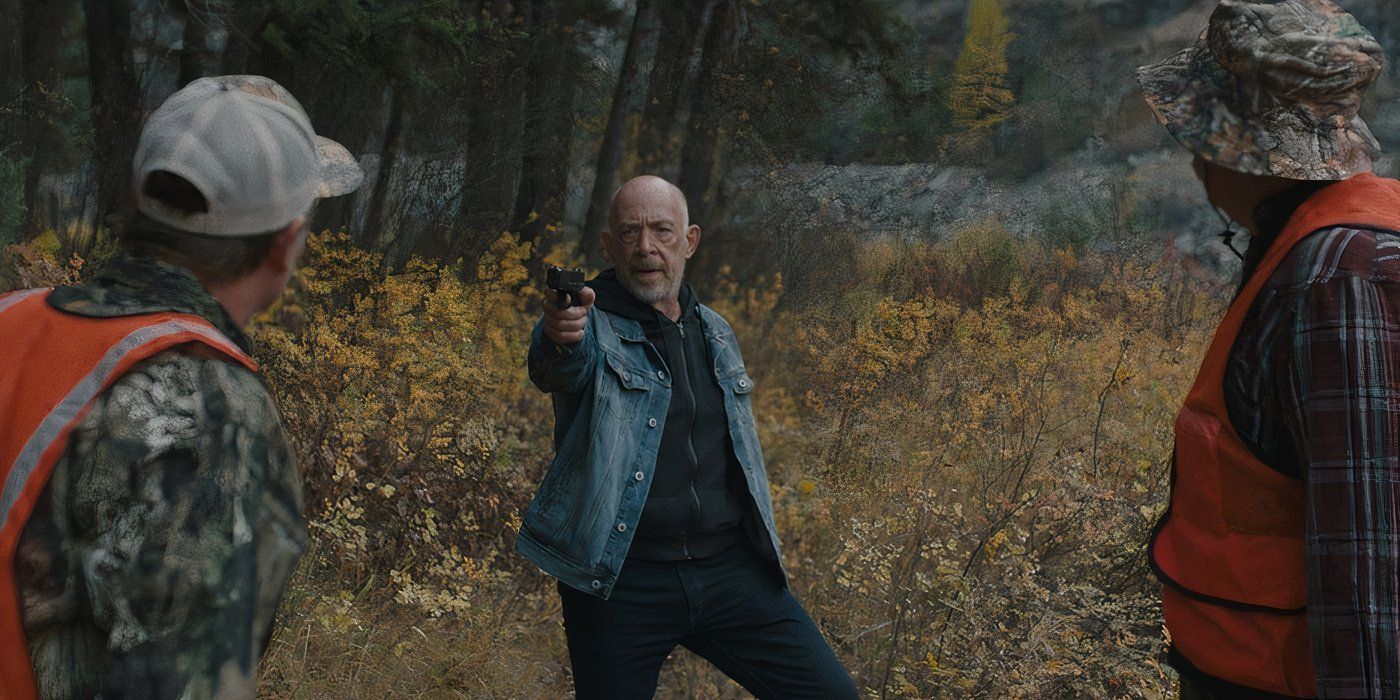 J.K. Simmons in a marsh, pointing a pistol at two hunters in camo and orange whose backs are turned towards the camera.