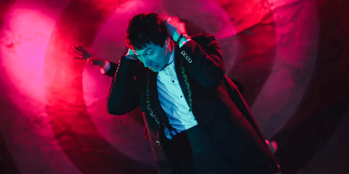 Adam Driver as Caesar Catalina holding his head with a red swirling background