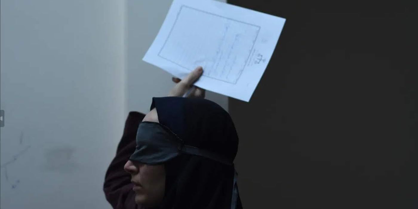 Mahsa Rostami blindfolded and holding up a piece of paper in The Seed of the Sacred Fig.