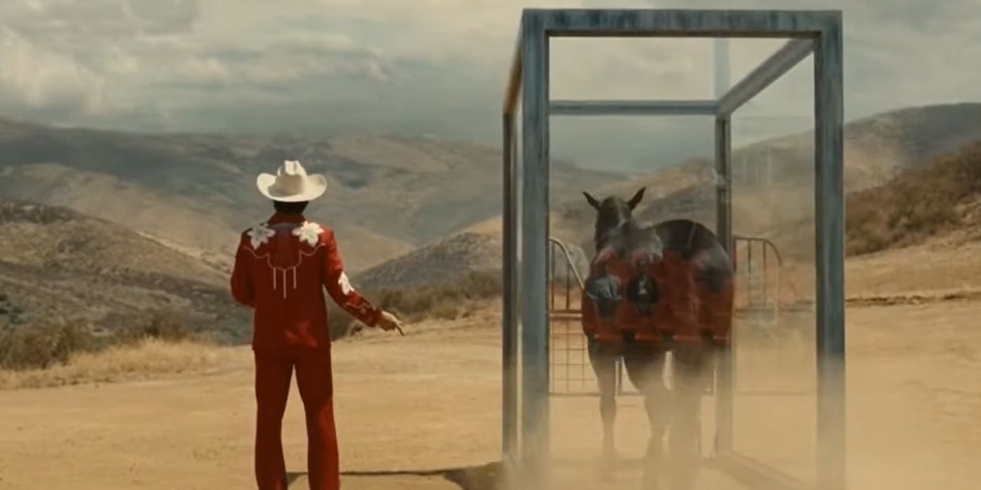 Jupe Park, played by Steven Yeun, stands next to a horse in a glass enclosure in Nope