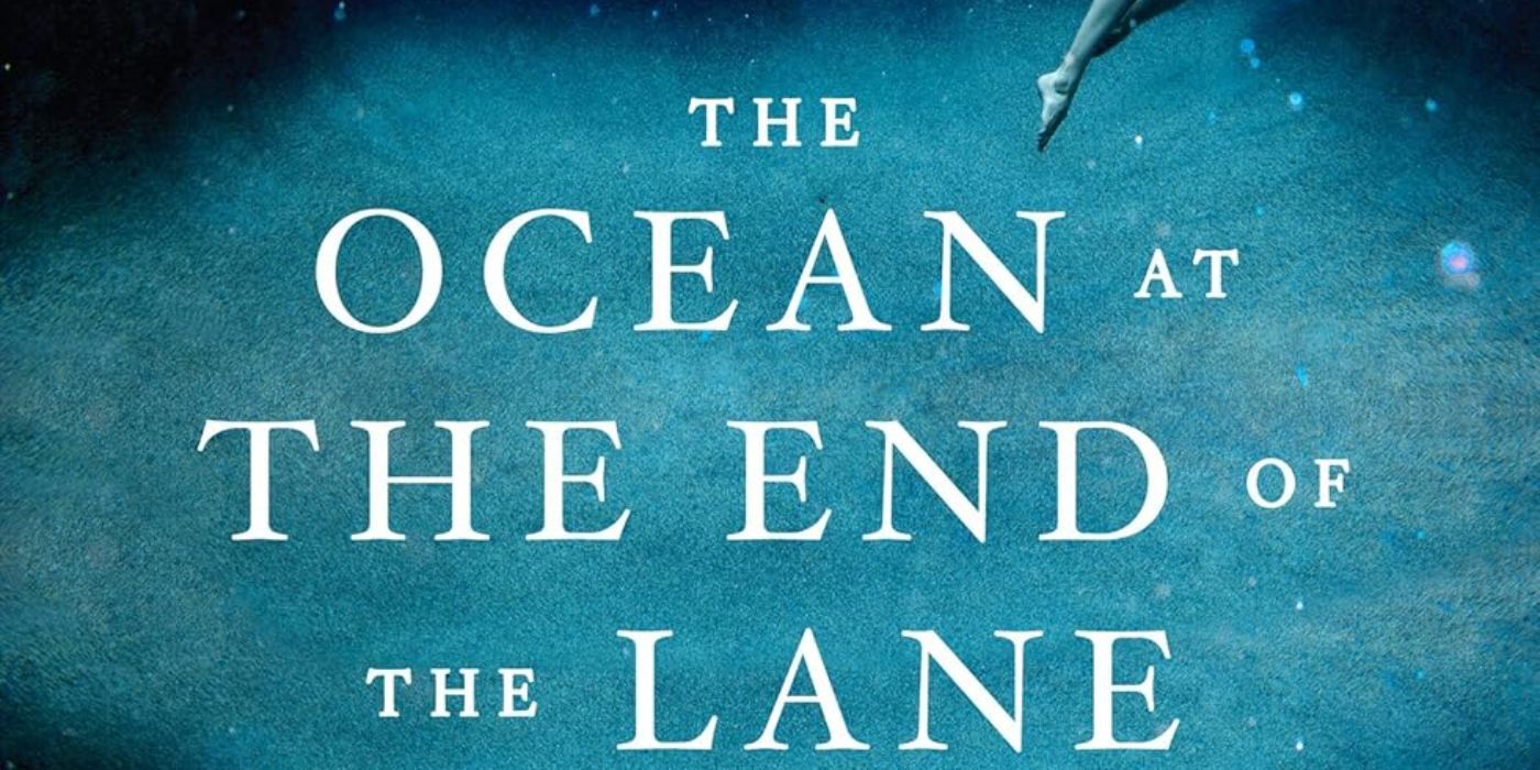 The words, "Ocean at the End of the Lane," are in white. The words are over sand at the bottom of an ocean. In the corner, a young girl wearing a white dress is shown floating in the water.