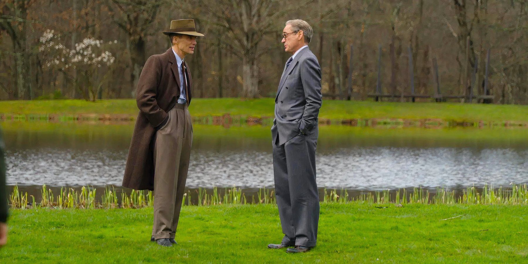 Robert Oppenheimer and Lewis Strauss confer on the grass at Princeton University in Oppenheimer
