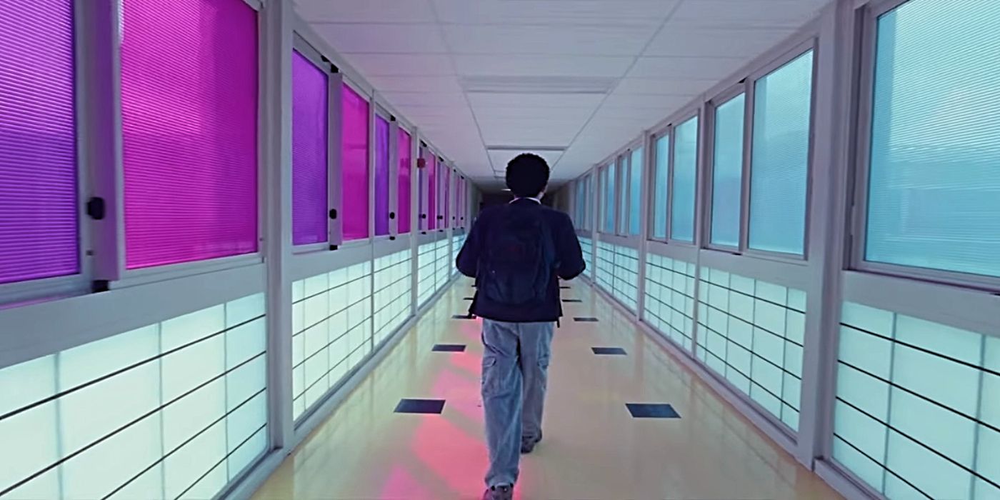 Owen walks down a hallway with pink windows on one side and blue on the other in I Saw the TV Glow