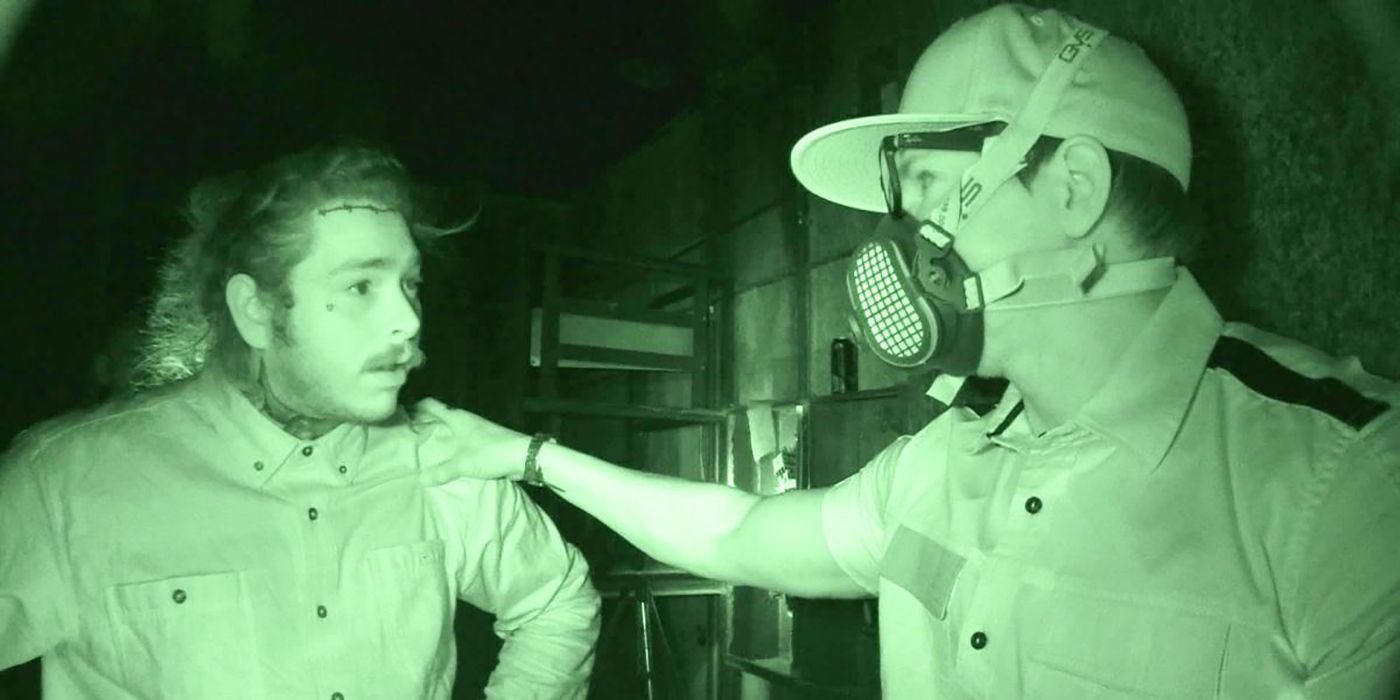 Post Malone looking scared talking to another man in a face mask with a night vision camera filming in a scene from Ghost Adventures.