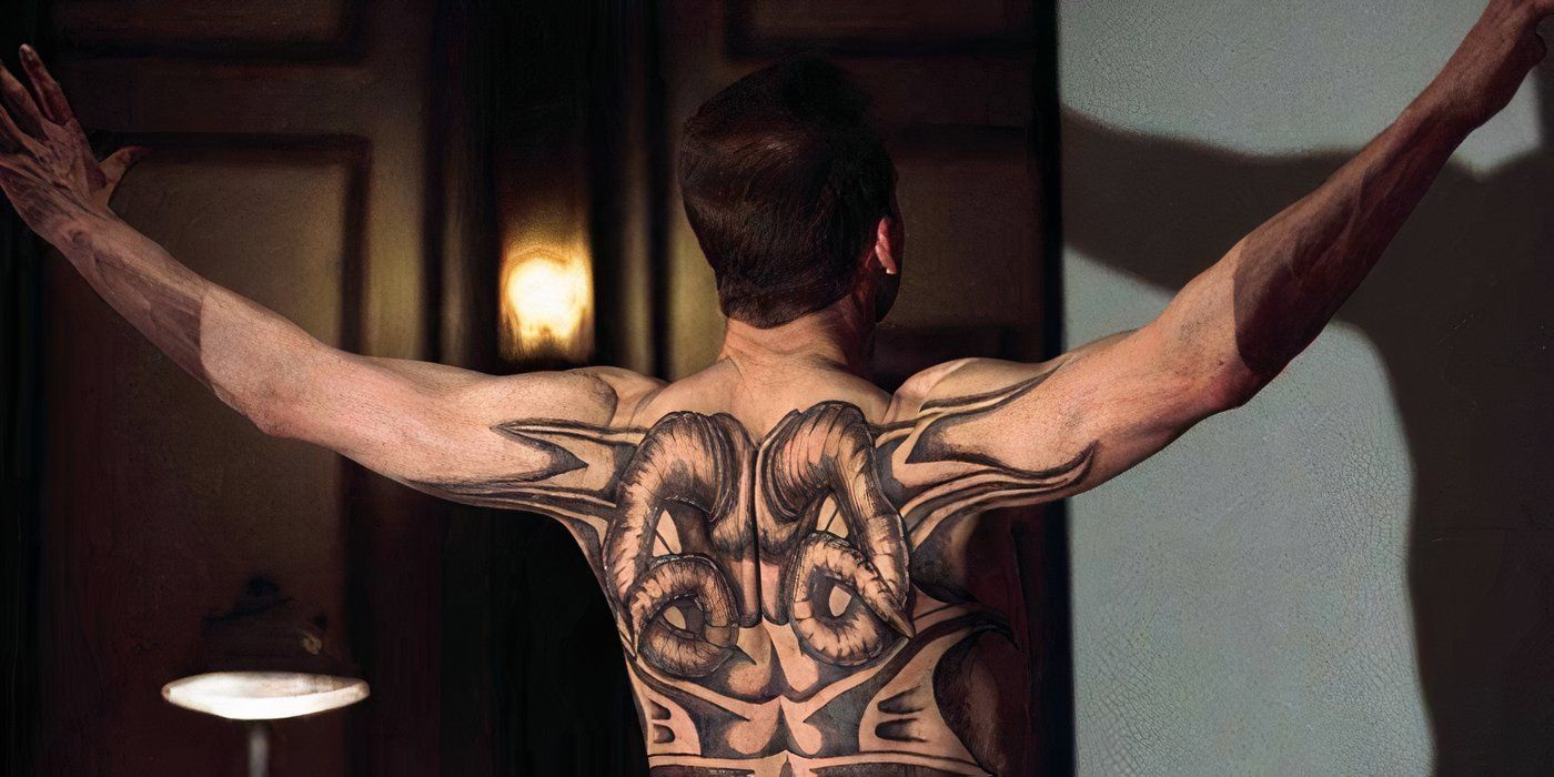 Francis Dollarhyde stands with his arms spread wide, his heavily-tattooed back facing the camera 