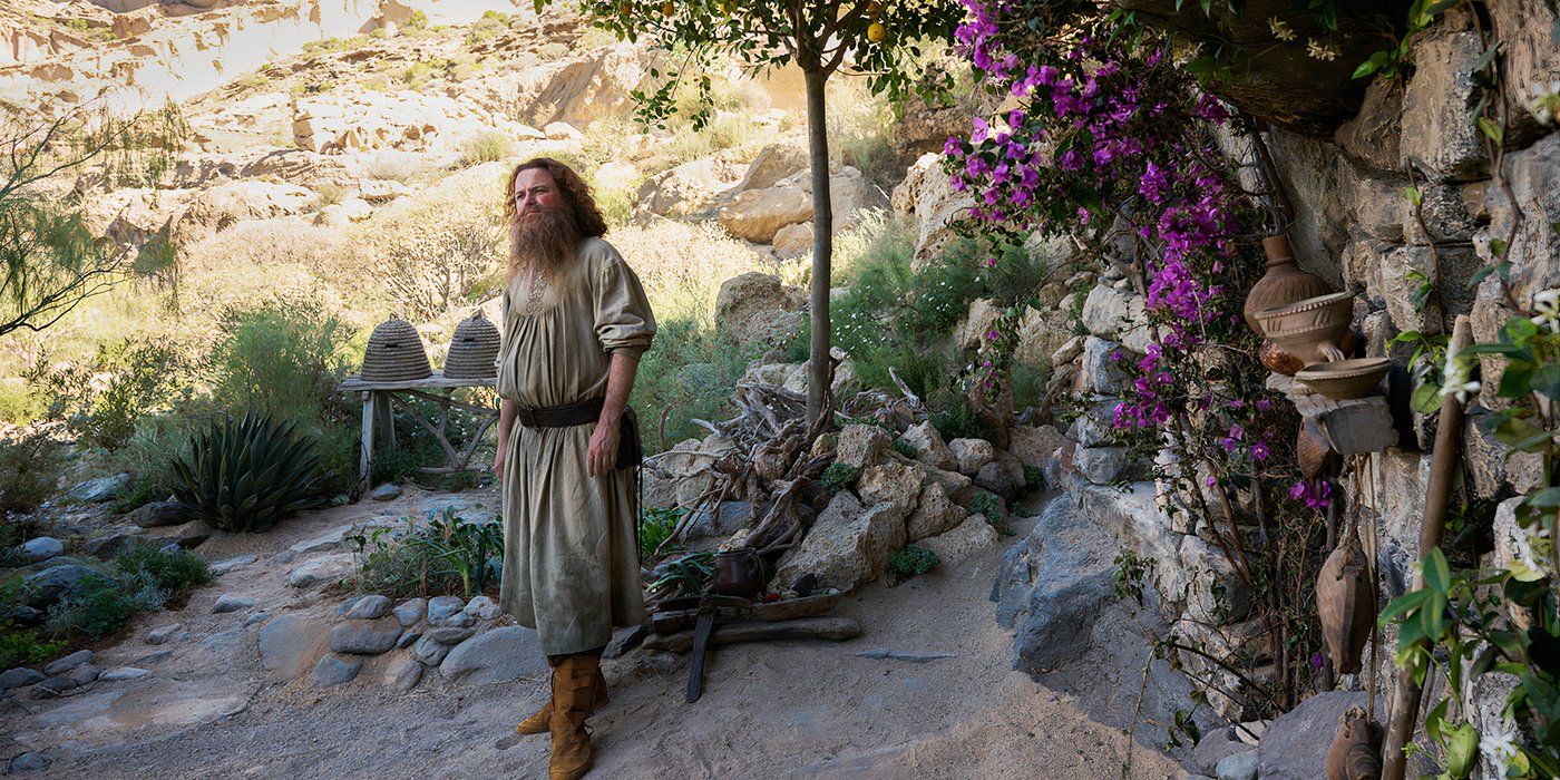 Rory Kinnear as Tom Bombadil in The Rings of Power standing outside near foliage