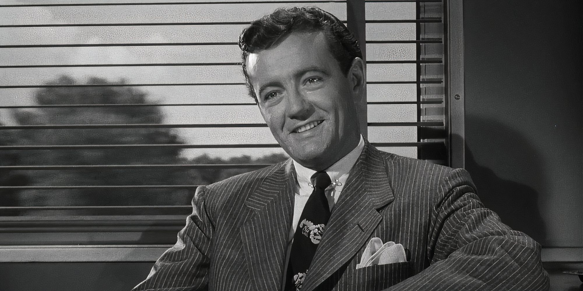 Robert Walker como Bruno Anthony sonríe ampliamente en Strangers (1951)