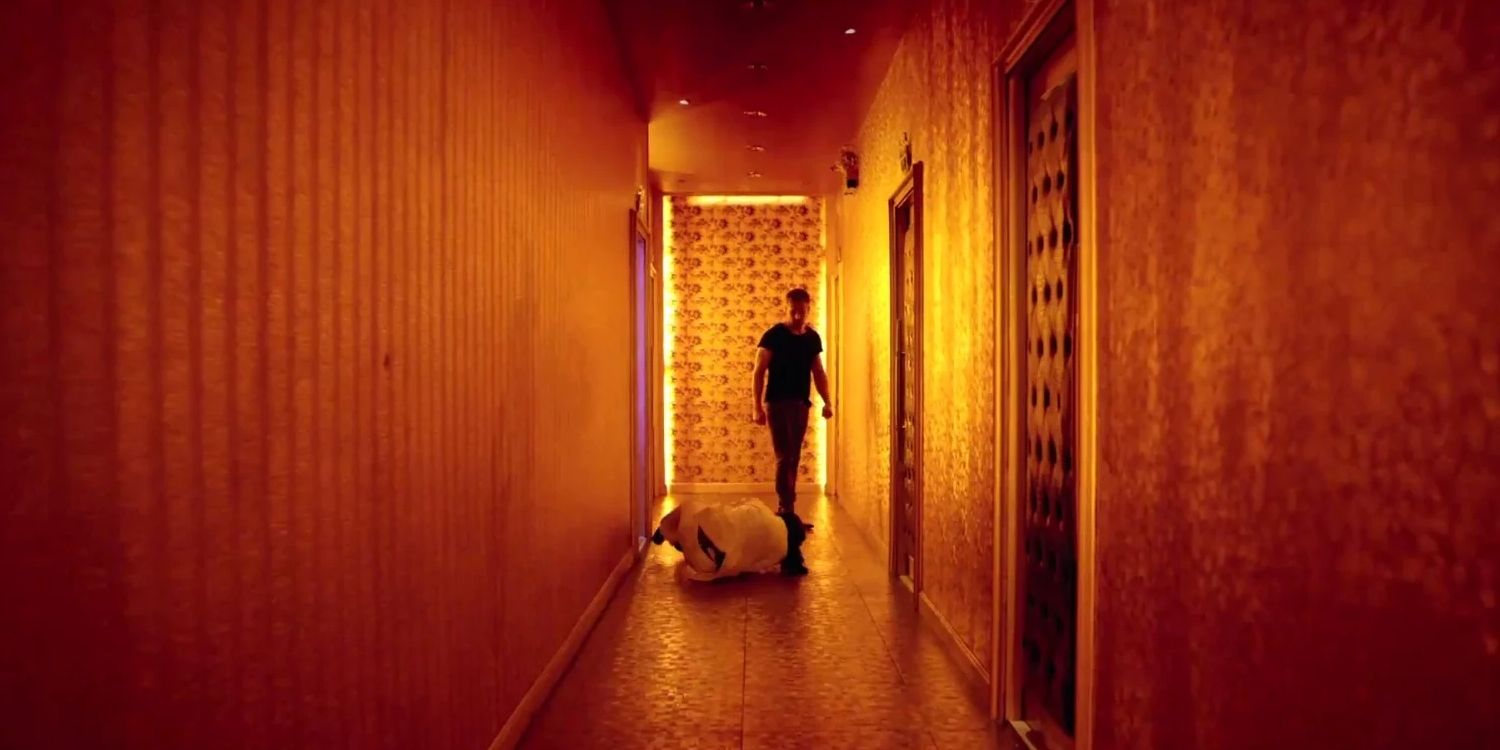 A man standing in a hallway next to an unconscious body In Only God Forgives