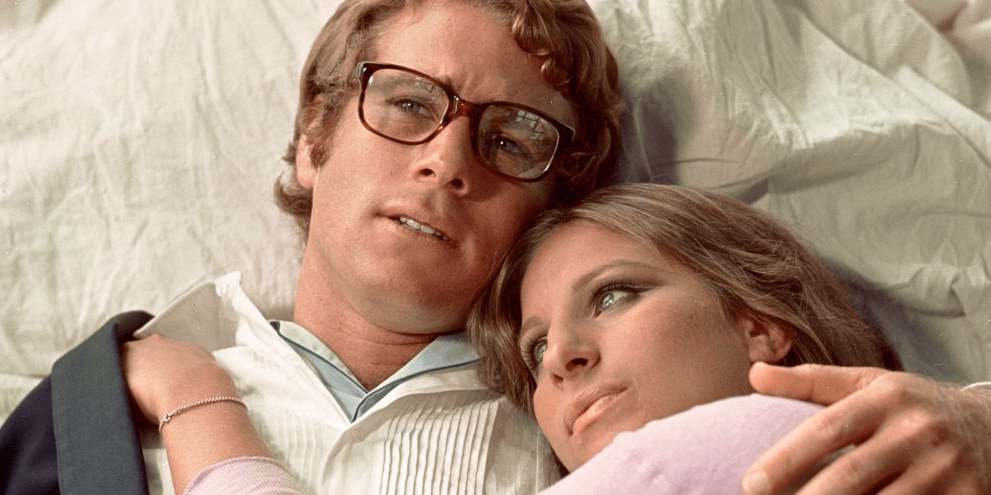 Ryan O&rsquo;Neal holding Barbra Streisand while lying down together in What&rsquo;s Up, Doc, 1972.
