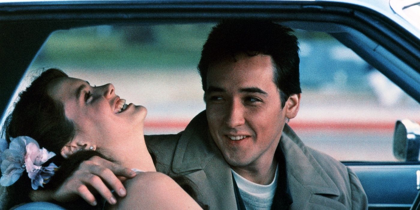 John Cusack and Ione Skye sit in a car together and laugh and smile in Say Anything.