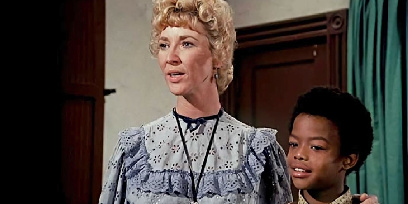 Miss. Beadle (Charlotte Stewart) talking to the class with her arm around Solomon Henry (Todd Bridges) on Little House on the Prairie