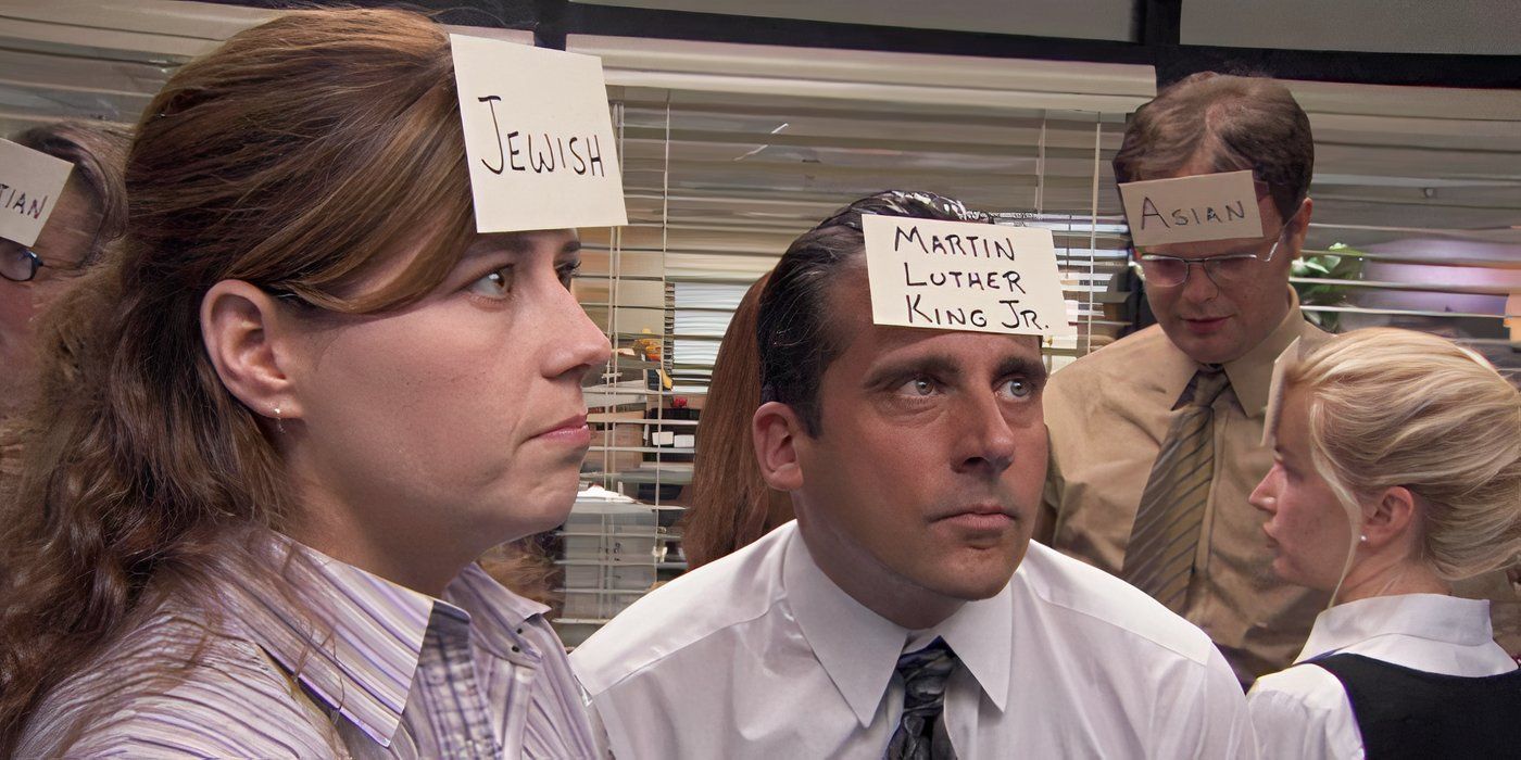 Pam (Jenna Fischer) wearing a note on her head that says "Jewish" and looking uncomfortable while Michael (Steve Carell) stands nearby wearing a note that says "Martin Luther King Jr." on The Office