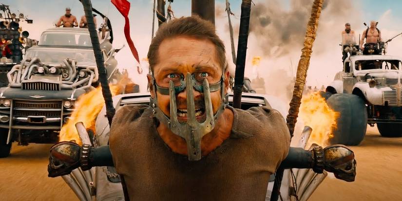 Max, played by Tom Hardy, strapped to the front of a vehicle with mask on in Mad Max: Fury Road (2015).