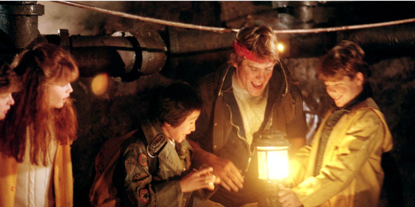 Josh Brolin, Ke Huy Quan, Sean Astin como Brand, Data y Mikey mirando un mapa sosteniendo una luz en 'Los Goonies'