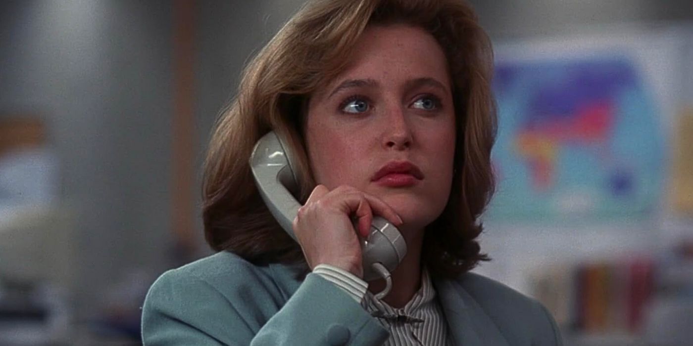 Gillian Anderson makes a call from her office wearing a light blue suit in The X-Files