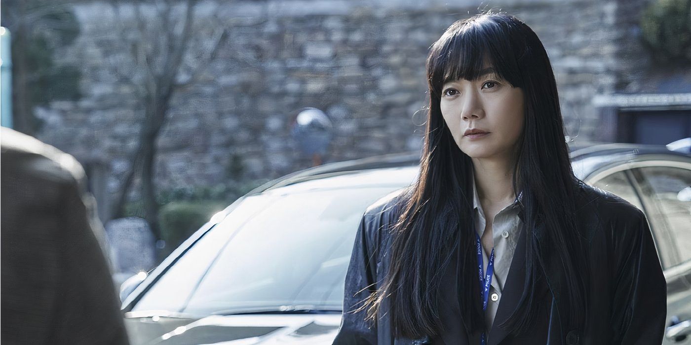 Bae Doona shown standing in front of a car while talking to someone off-screen in a scene from the series 'Stranger'