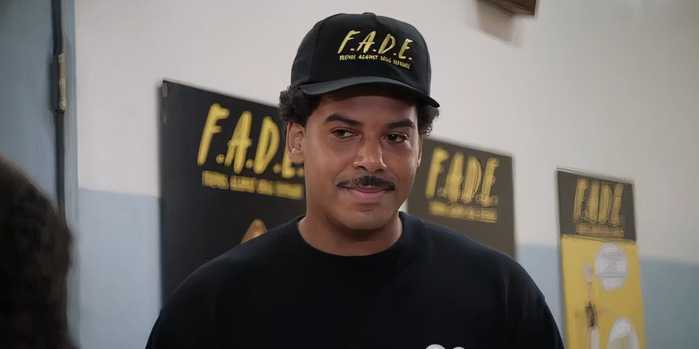 Zack Fox as Tariq Temple in Abbott Elementary wearing a black F.A.D.E. cap and t-shirt.