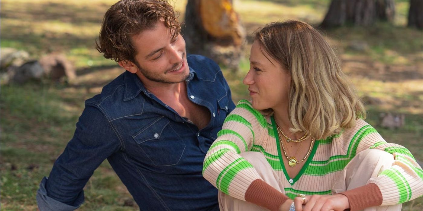 A man looking at a woman lovingly while they sit on the ground