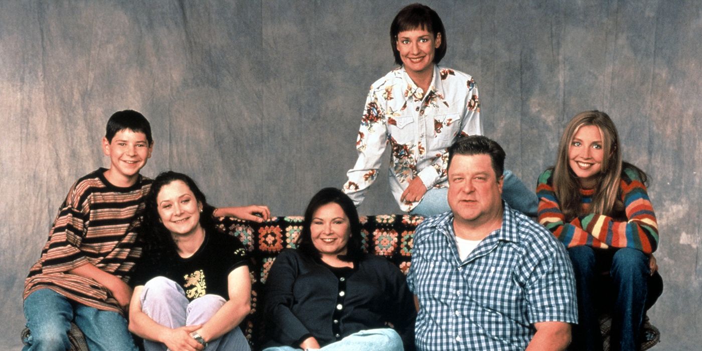 The Conners, the cast of Roseanne, sitting on a couch posing for a photo