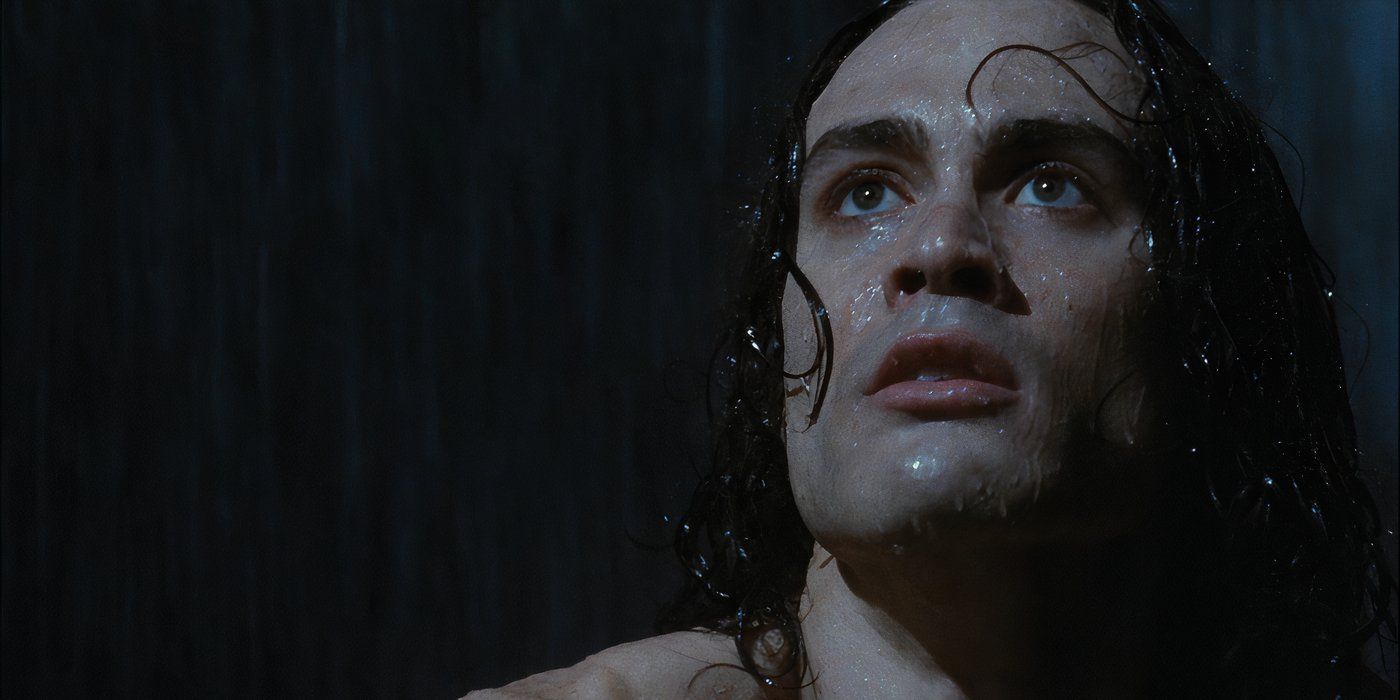 A close-up of Eric Draven (Brandon Lee) staring to the left in the rain in The Crow, not wearing his normal white makeup