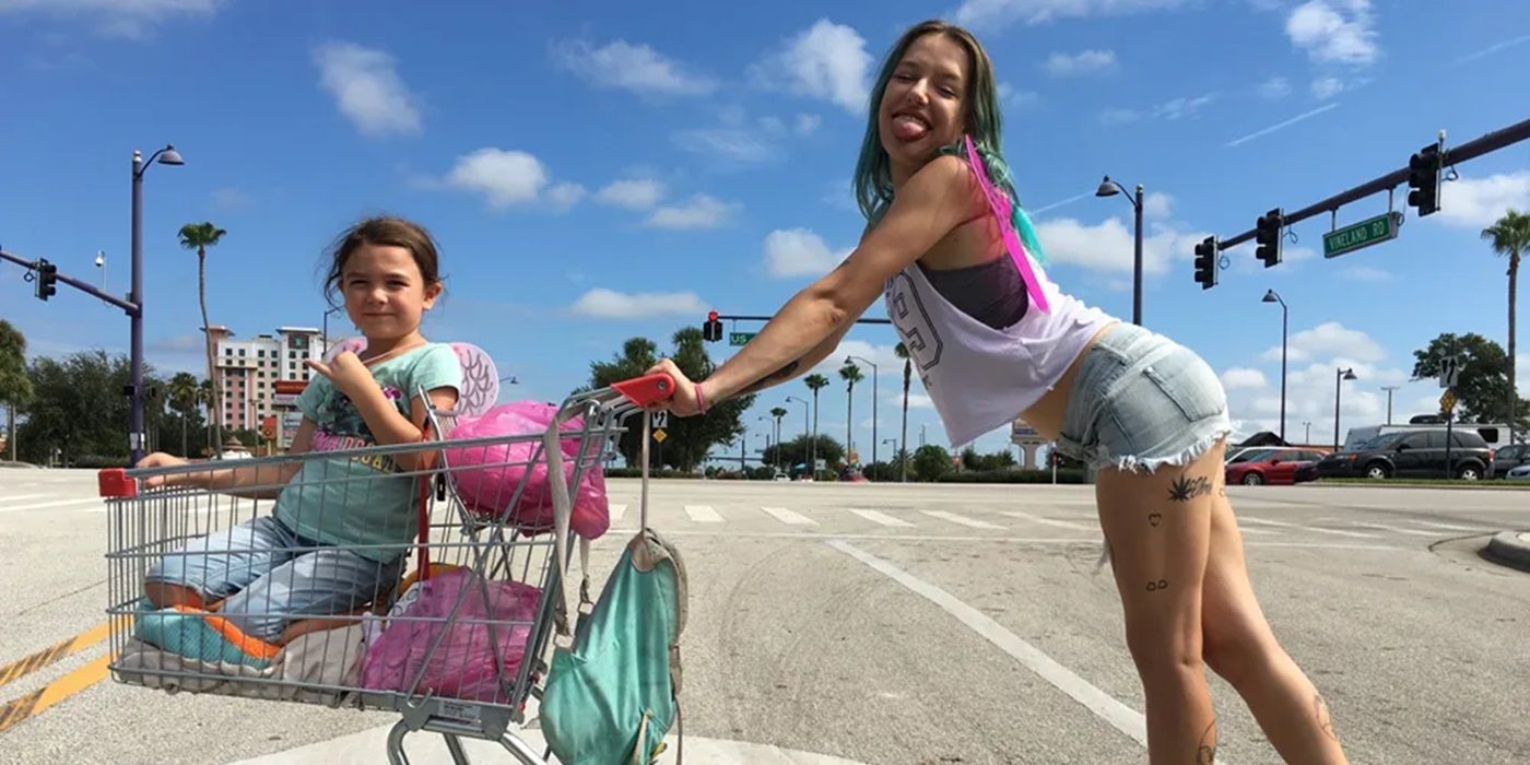 Bria Vinaite pushing a cart with Brooklynn Prince seated inside on a cropped poster of The Florida Project