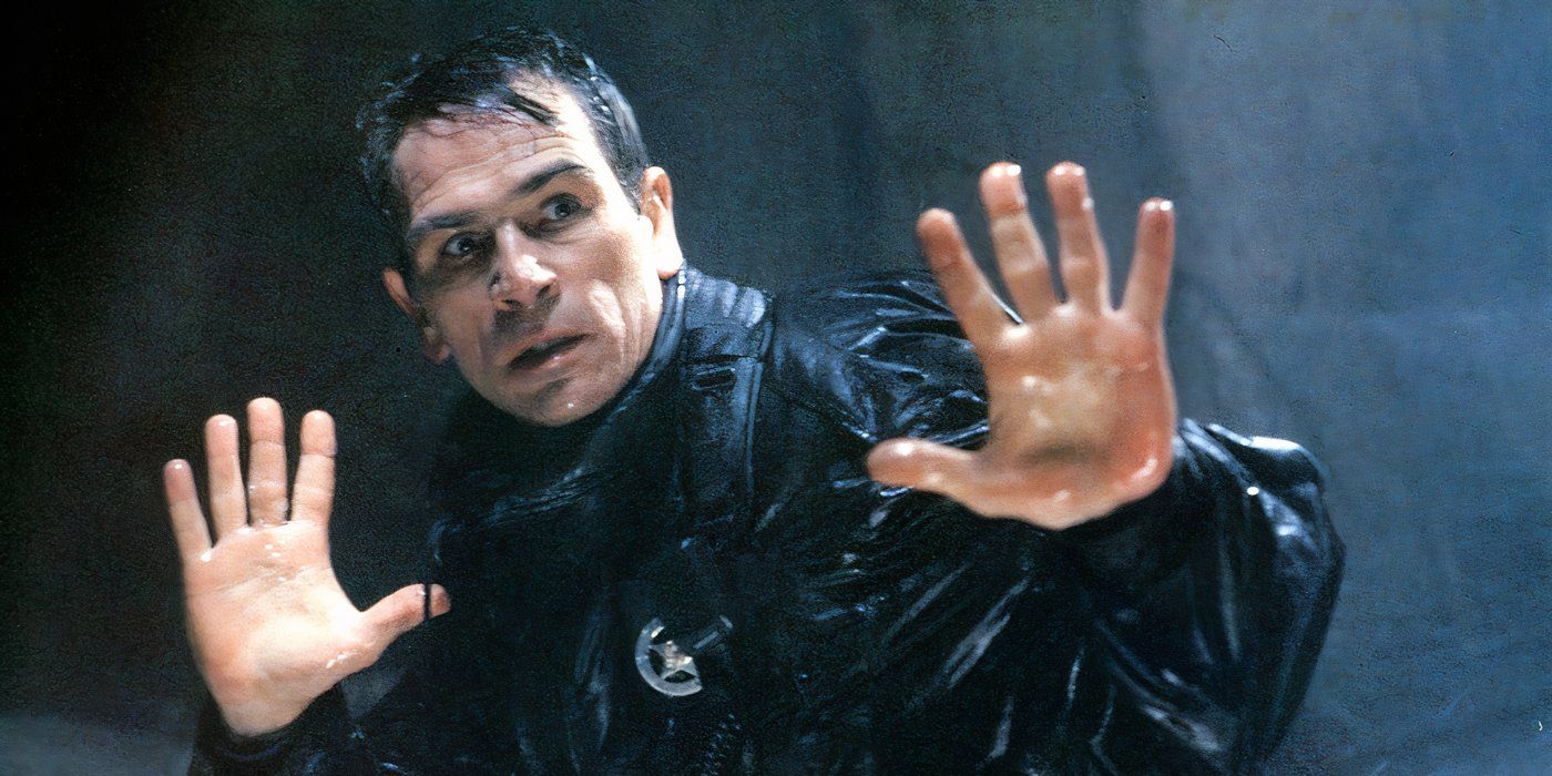 Tommy Lee Jones as Samuel Gerard, dripping with water and holding his hands up in surrender in The Fugitive