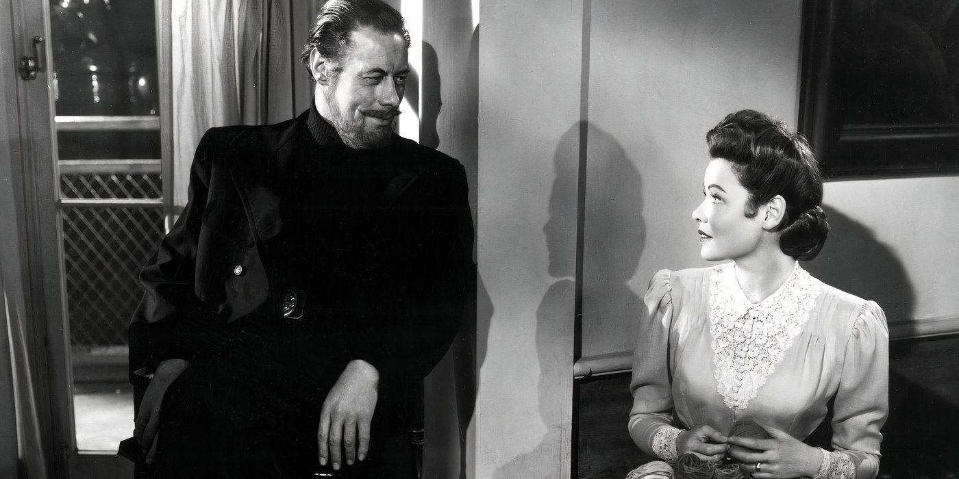 Daniel Cregg (Rex Harrison) leaning against a wall corner and smiling at Lucy Muir (Gene Tierney), who's sitting down on his right and smiling back at him, in The Ghost and Mrs. Muir