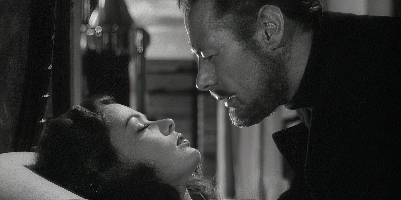 A close up of Daniel Cregg (Rex Harrison) leaning down close to a sleeping Lucy Muir's (Gene Tierney) face in The Ghost and Mrs. Muir