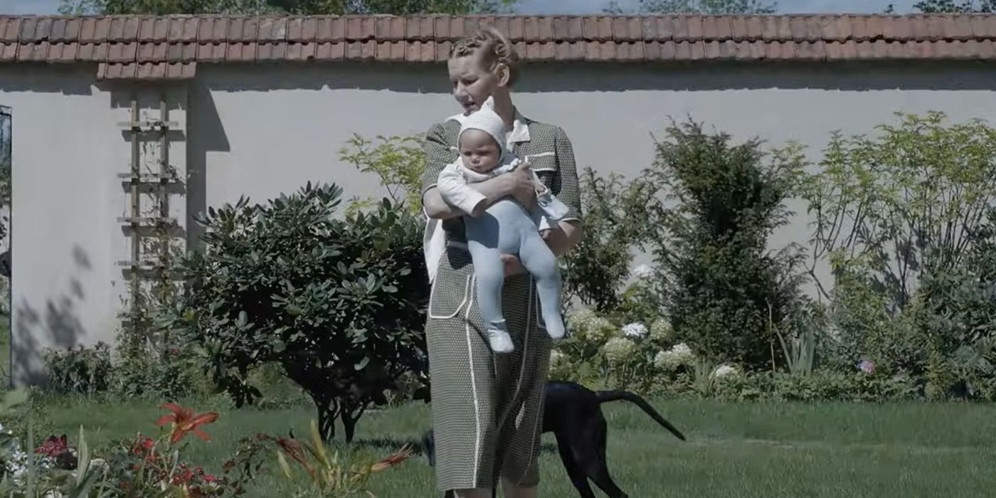 Sandra Hüller as Hedwig Höss walking in her garden while holding her baby in The Zone of Interest