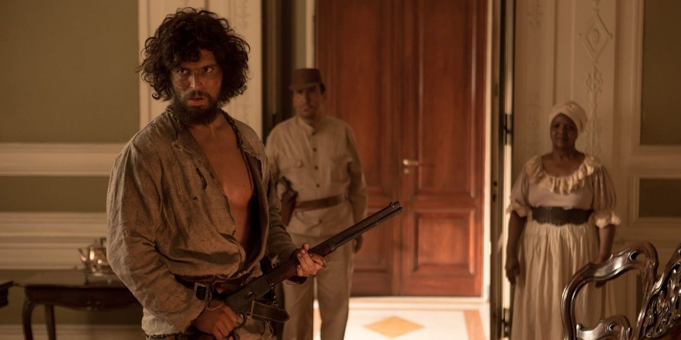 Cabeleira holding a gun in a fancy house in The Killer (2017)