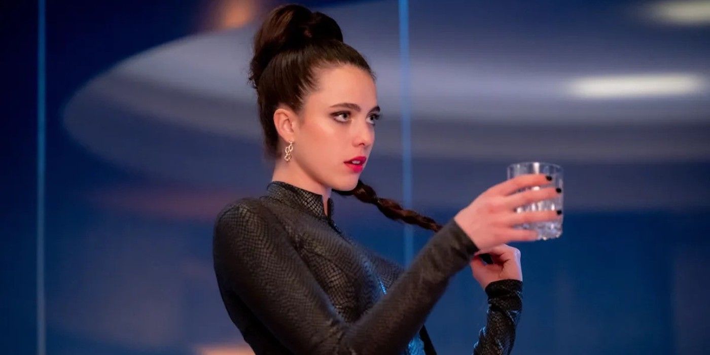 Margaret Qualley as Sue holding a drink in one hand and her long ponytail in the other in The Substance.