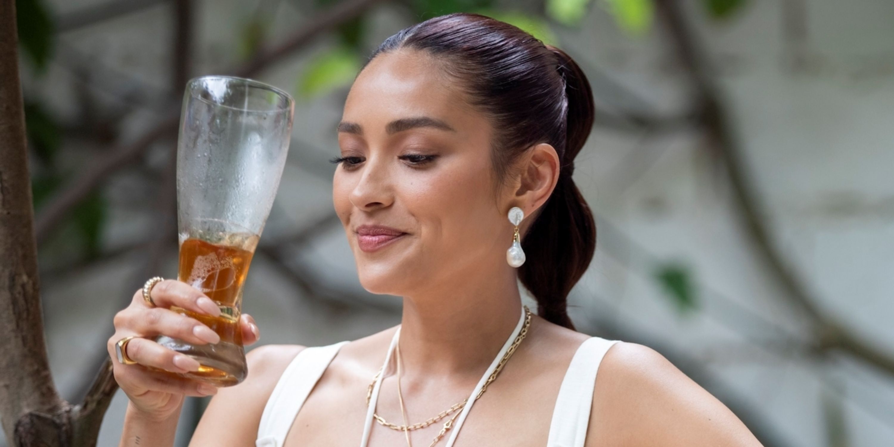 Shay Mitchell looking at her beer as the host of the travel series Thirst with Shay Mitchell