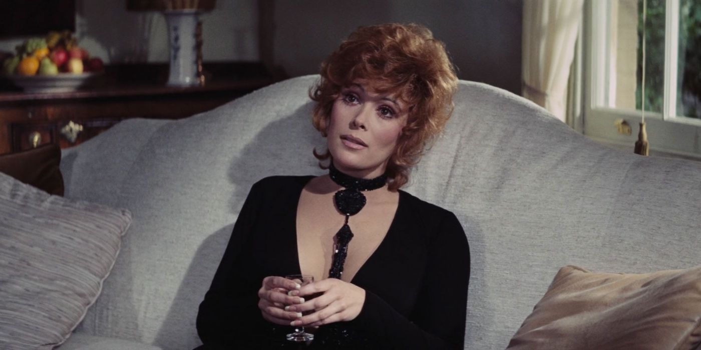 tiffany case (Jill st. John) sits on a couch with a glass of wine